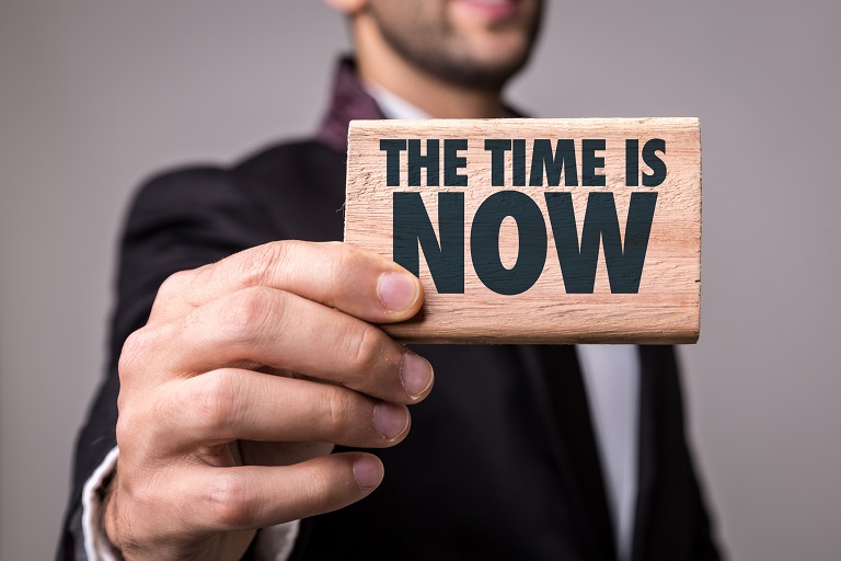 man holding a writing “The Time is Now"