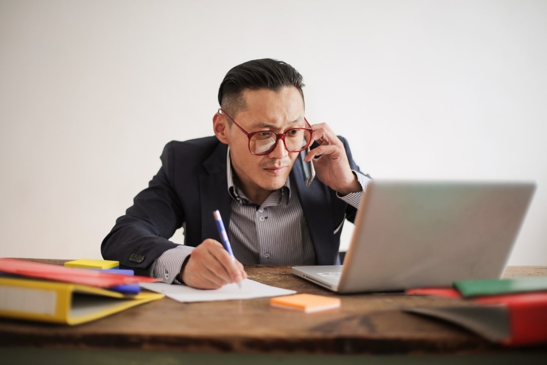 business man using laptop and phone to work from home