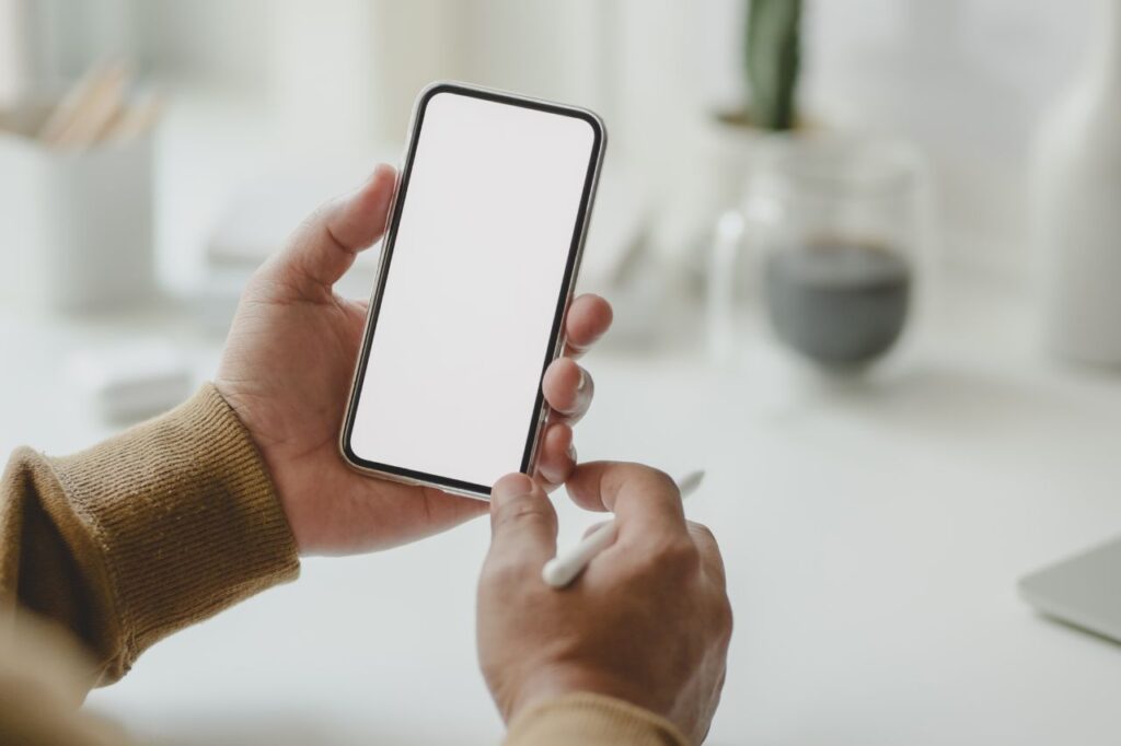 Person holding a smartphone and a pen