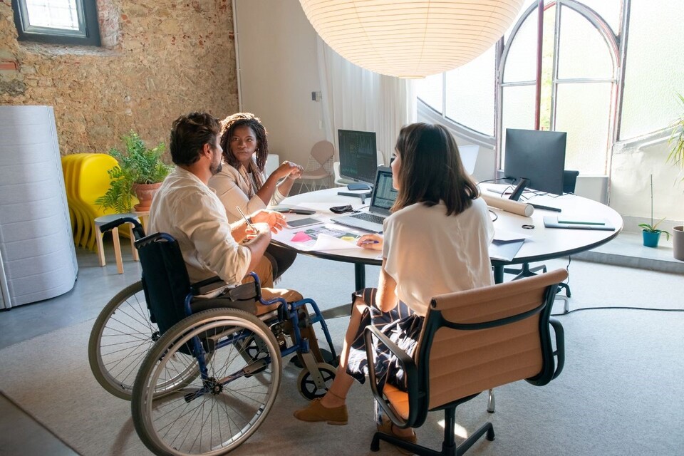 Two women and a man in a wheelchair having a conversation